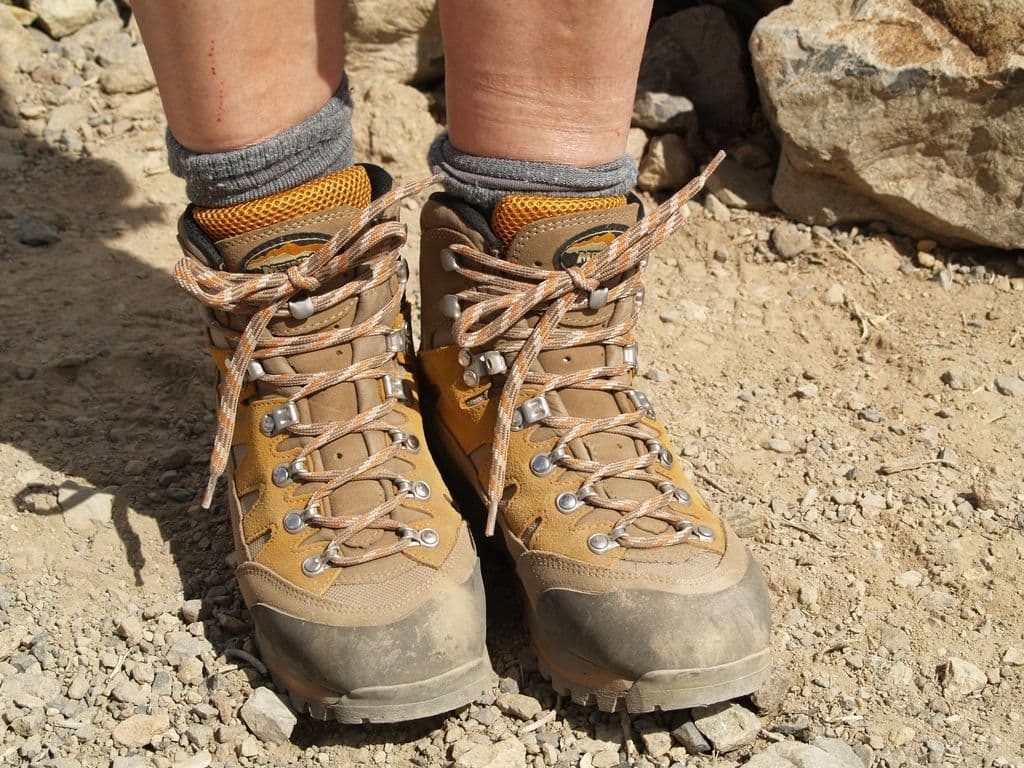 Hiker standing on rocky ground in tobacco-tan leather hiking boots with orange laces
