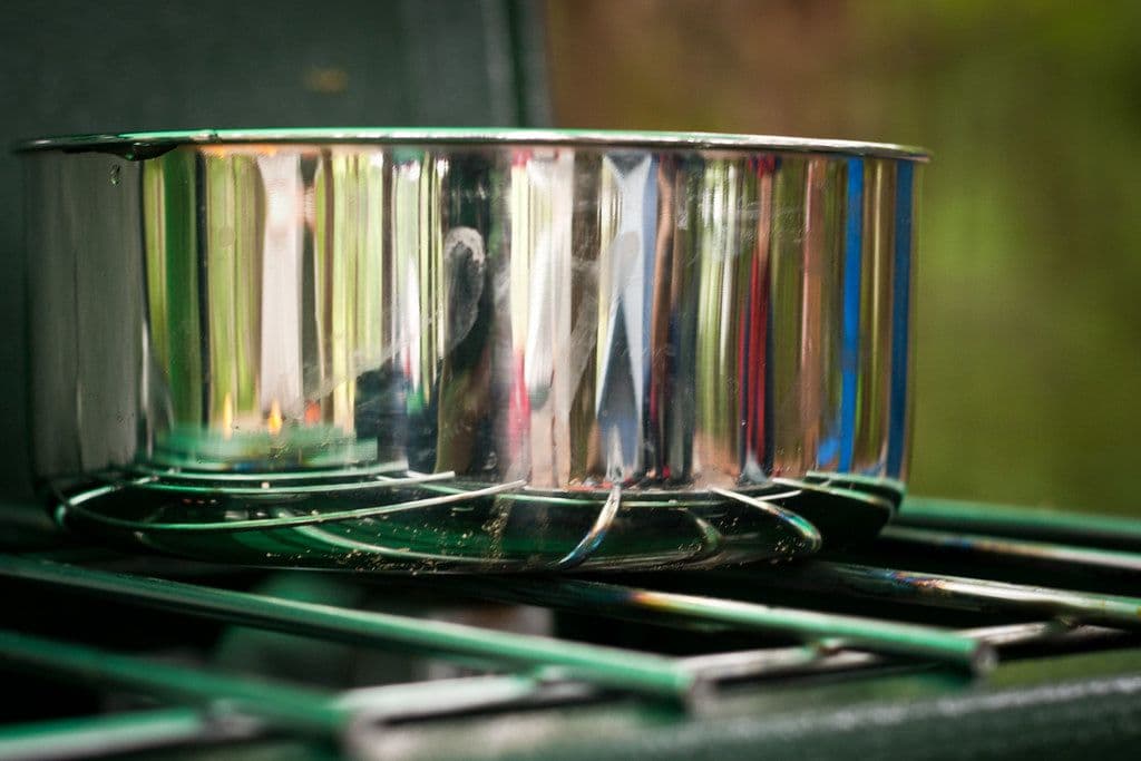 Basecamp Titanium Cook Kit, alternate view: Shiny nesting steel pots stacked on the green grate of a camp stove