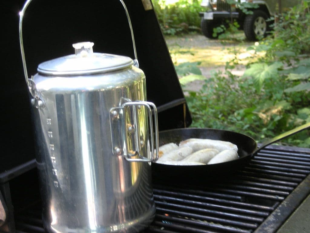 Thumbnail: Aluminium percolator coffee pot beside a skillet on a camp grill