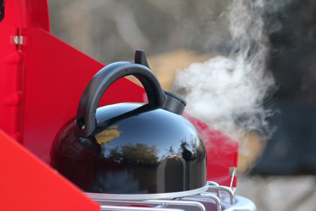 Thumbnail: Black kettle steaming on a red camp stove