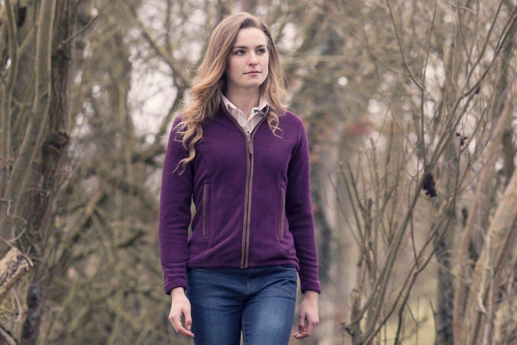 Woman walking through bare winter woods in a plum full-zip fleece