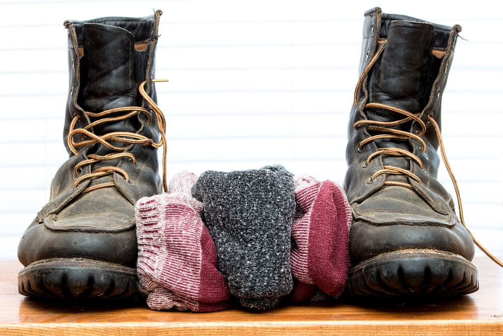 Merino Trail Socks (2-pack), alternate view: Three pairs of folded wool socks tucked between a pair of laced work boots