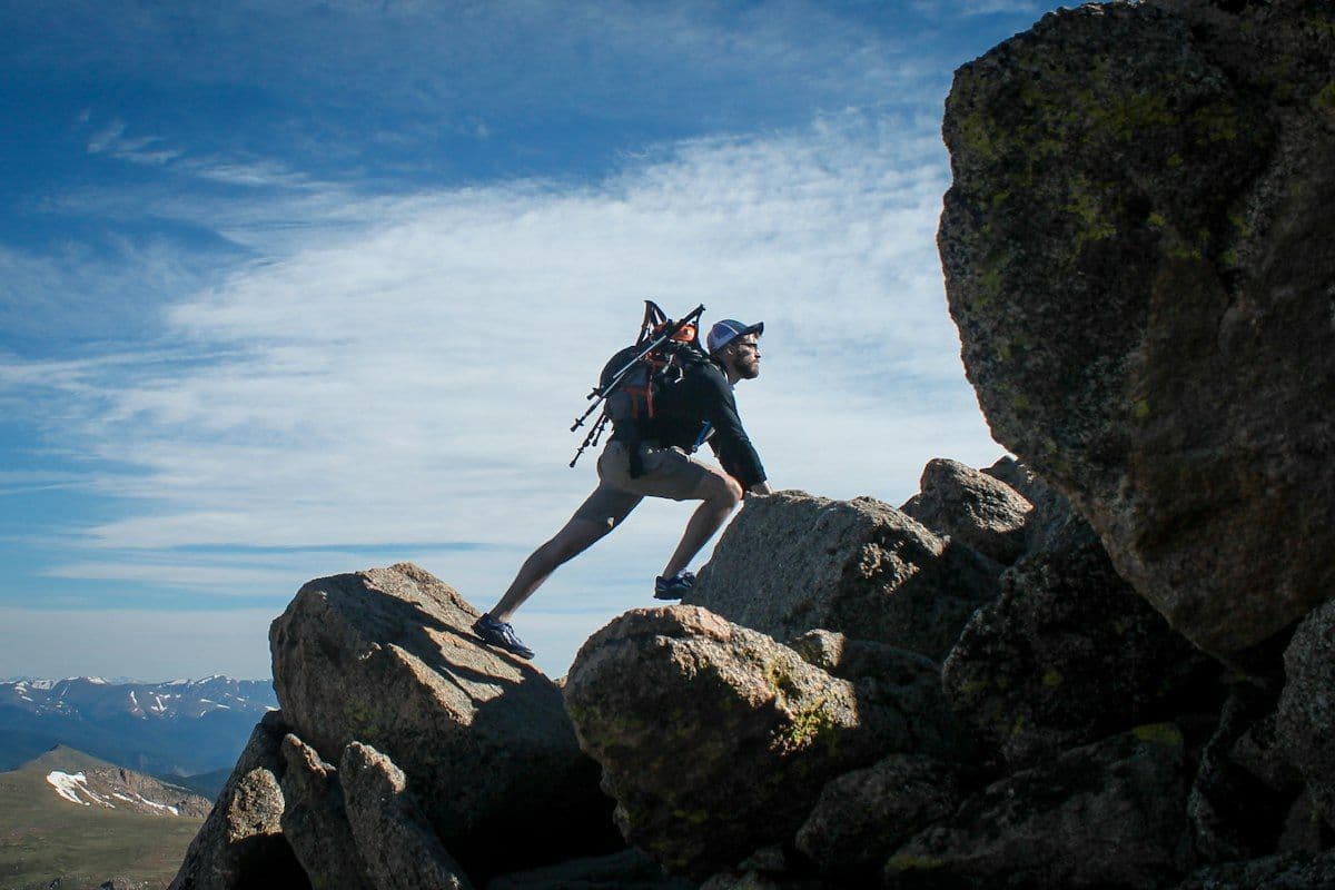 Hiker with a backpack scrambling up a rocky outcrop